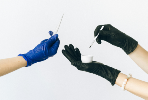two individuals wearing disposable gloves and holding small tools
