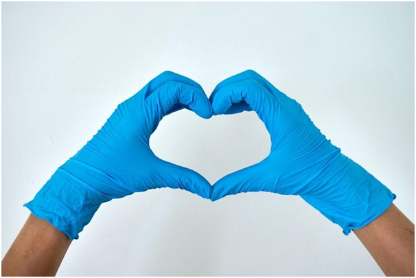 Nurse wearing latex gloves making the shape of a heart with her hands