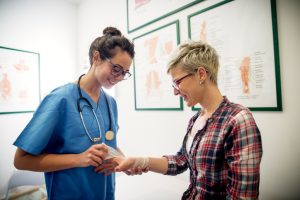 Professional carry medical nurse putting a bandage on a young girls injured hand.