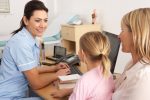 British nurse talking to young child and mother