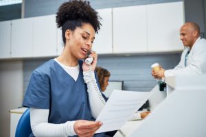 Healthcare Professional Talking on Phone in Reception Area with a Team