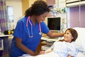 Young Girl Talking To Female Nurse In Hospital Room
