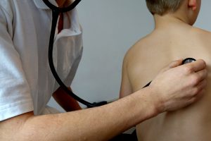 A respiratory therapist is listening to a child's internal sound made by lungs